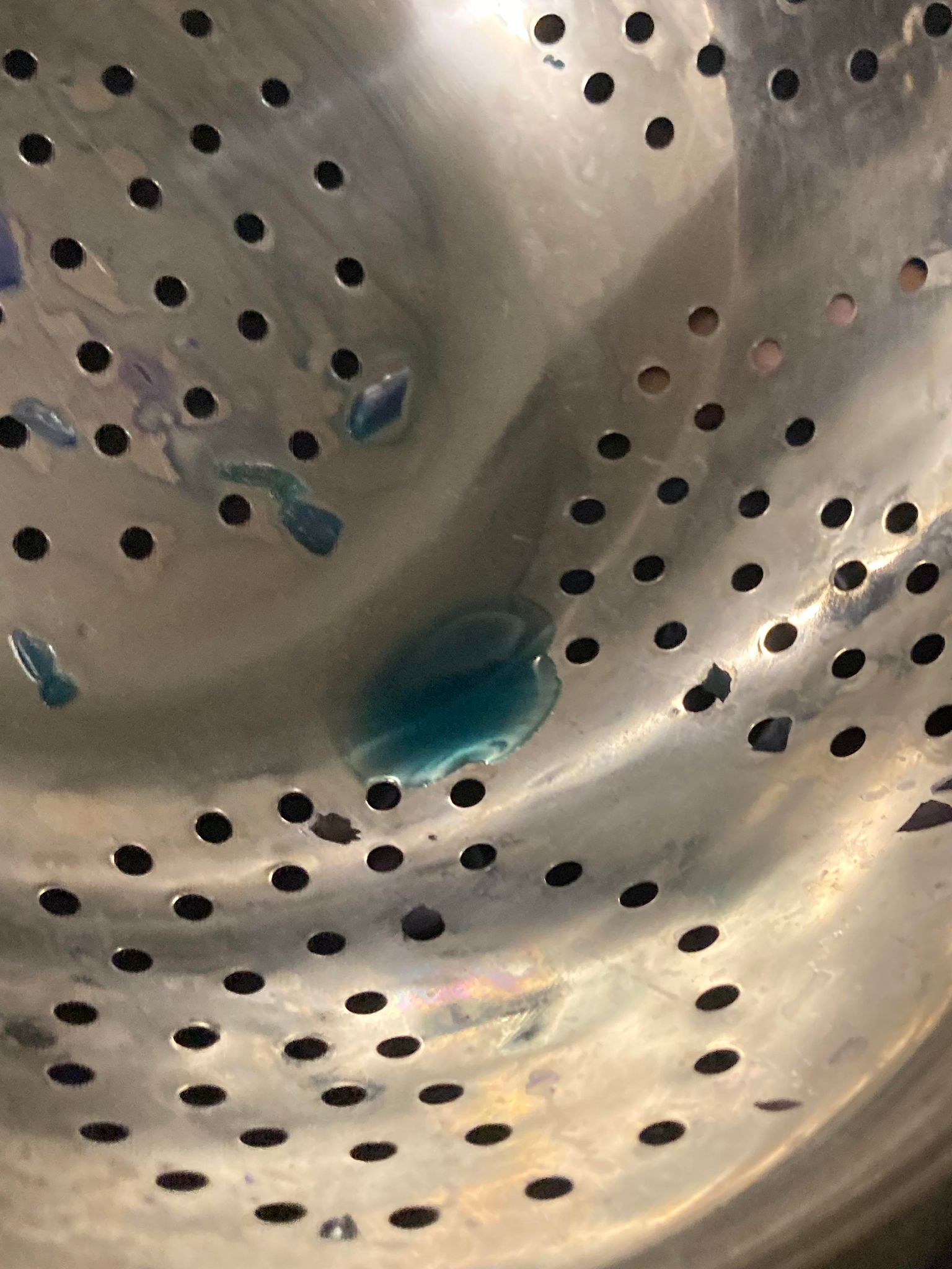 A strainer with a small amount of blue liquid in the bottom.